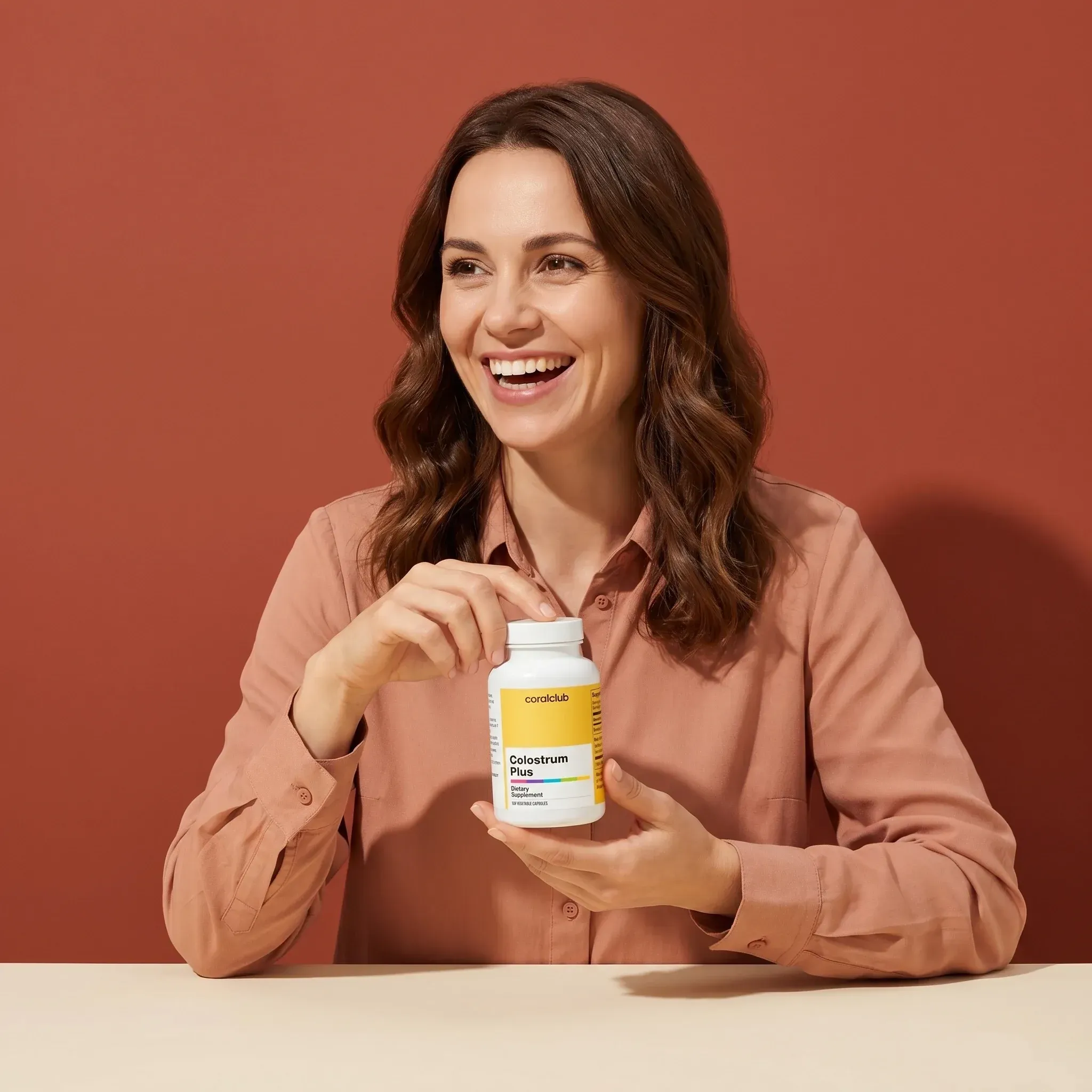 Femeie ținând flaconul de supliment Colostrum Plus pe un fundal cald, zâmbind.