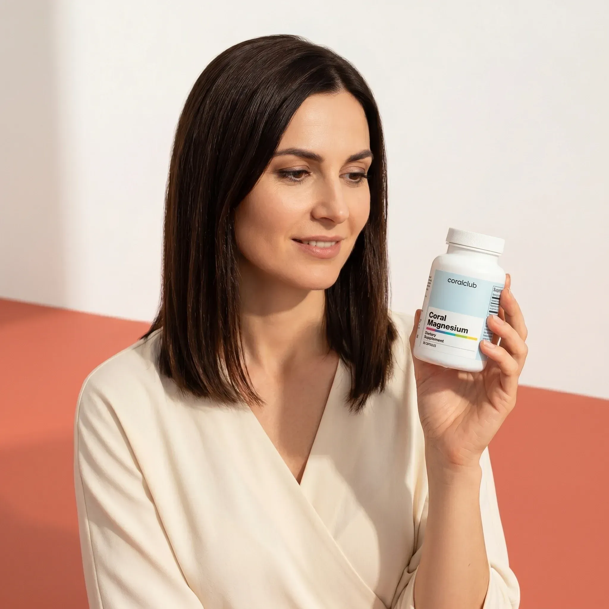Femeie ținând flaconul Coral Magnesium într-un decor modern și minimalist.