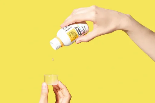 Vitamina C lipozomală turnată din flacon într-un pahar dozator